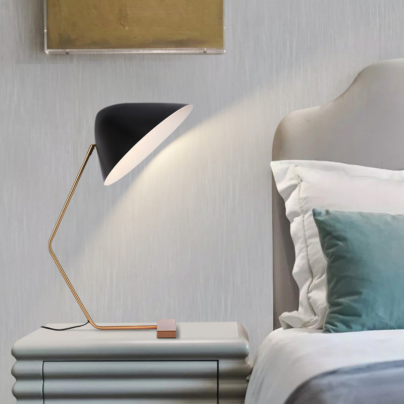 Black and gold curvilinear table lamp styled beside upholstered bed
