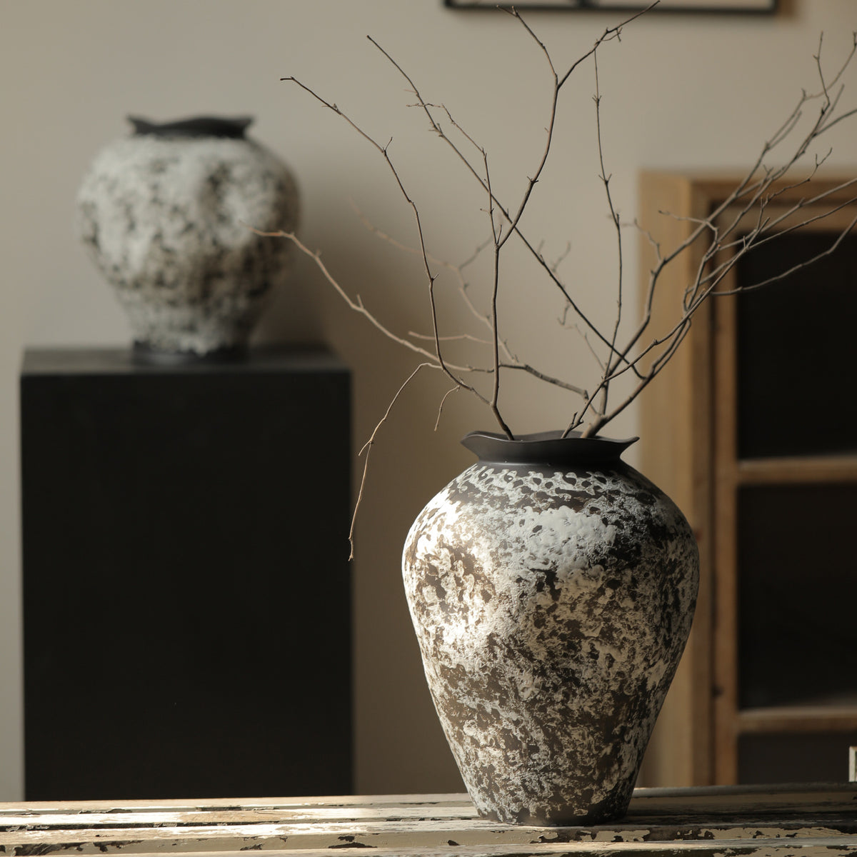 Black and white rustic ceramic vase styled on pedestal