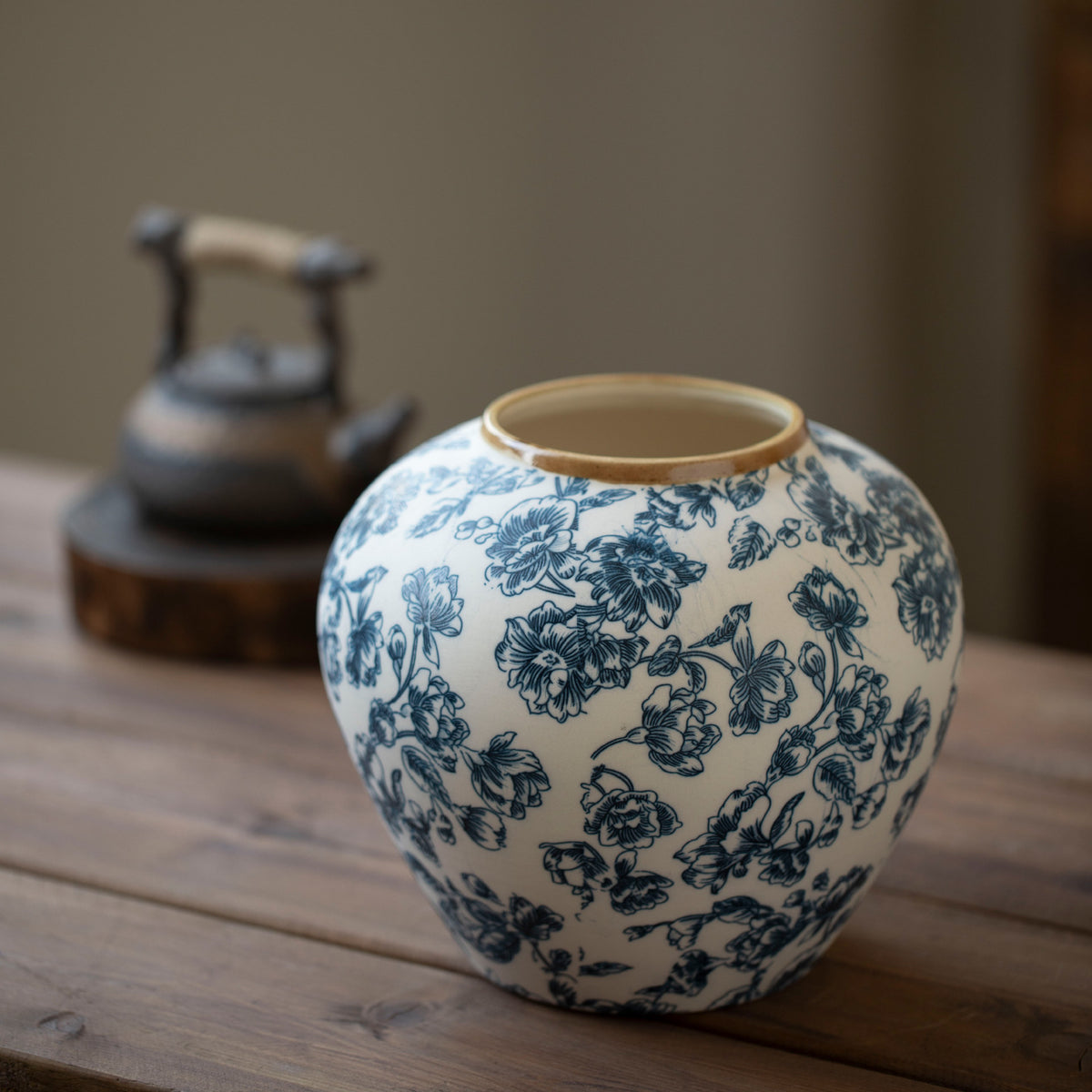 Small rounded blue botanical ceramic vase on dark wood table