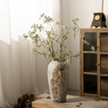 Tall weathered stone-effect ceramic vase with airy green branches