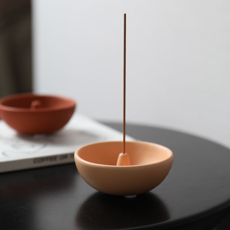 Light coffee ceramic incense bowl holding a thin incense stick