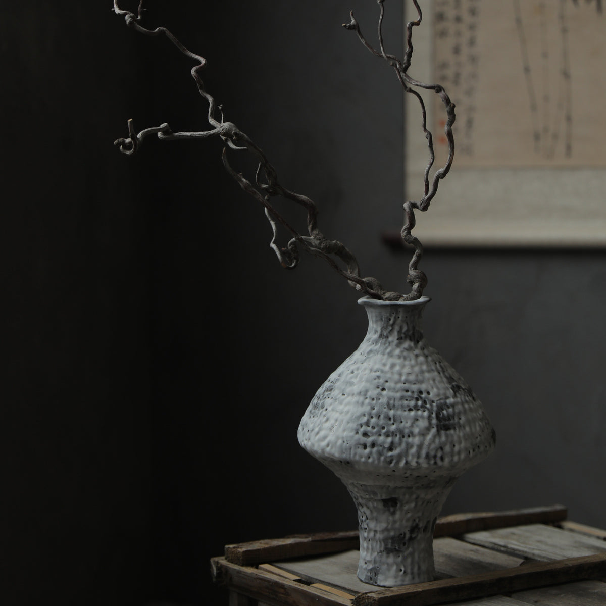 Mottled white hammered ceramic vase with sculptural branch arrangement