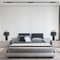Smoked acrylic petal table lamp with glossy black cylindrical base in bedroom