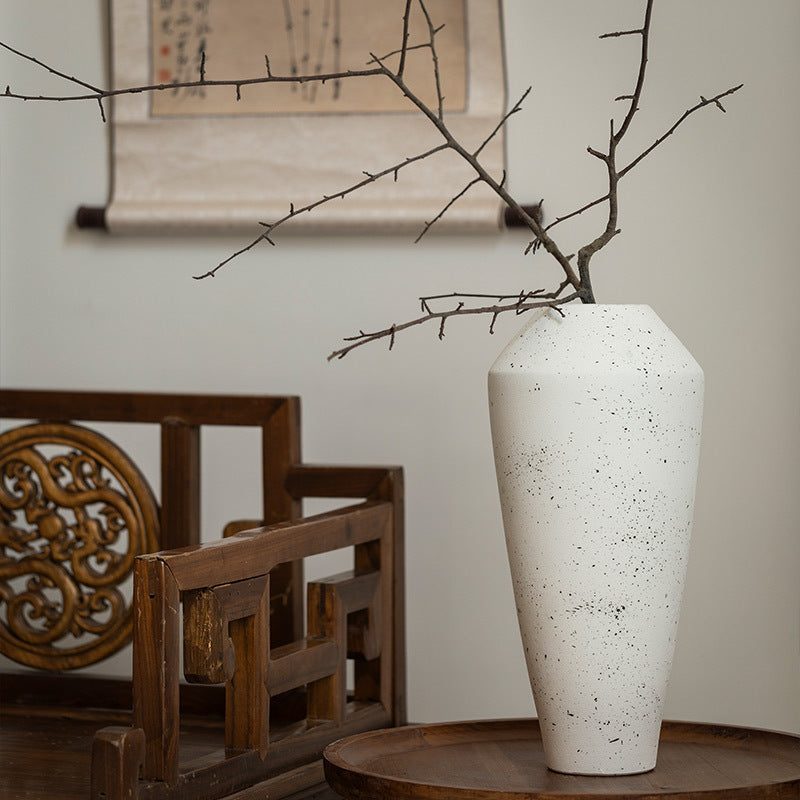Tall ivory white ceramic vase with bare branch arrangement