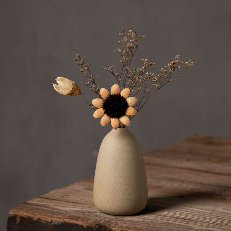 Rounded beige coarse-clay bud vase with dried flower arrangement