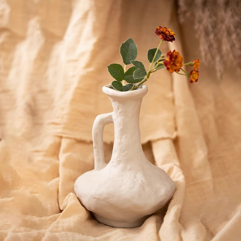 White ceramic handled vase styled with orange flowers for tabletop decor