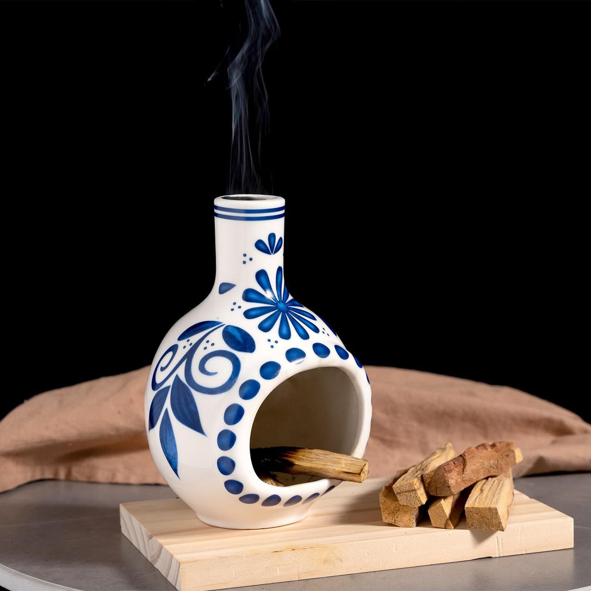 Blue and white floral ceramic Palo Santo and sage burner with smoke rising from neck