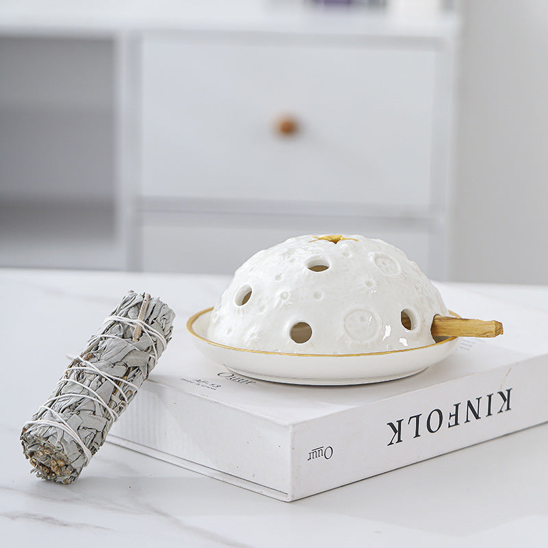 White ceramic covered incense burner styled with sage bundle on books