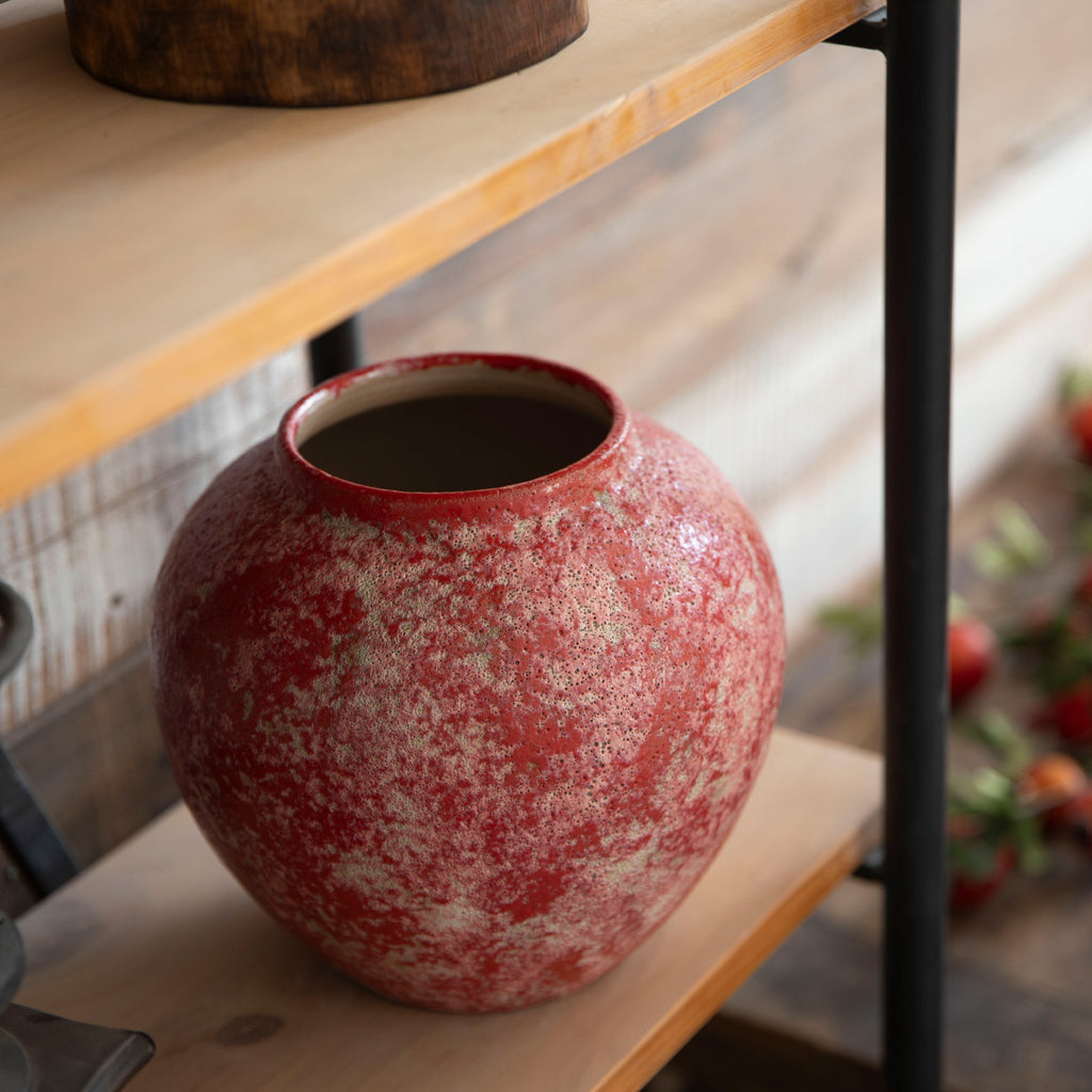 Small berry red rustic ceramic vase on dark wood shelf