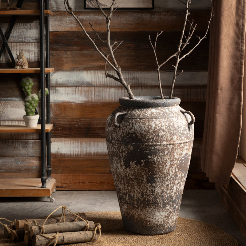 Large weathered ceramic floor urn with double handles and branches