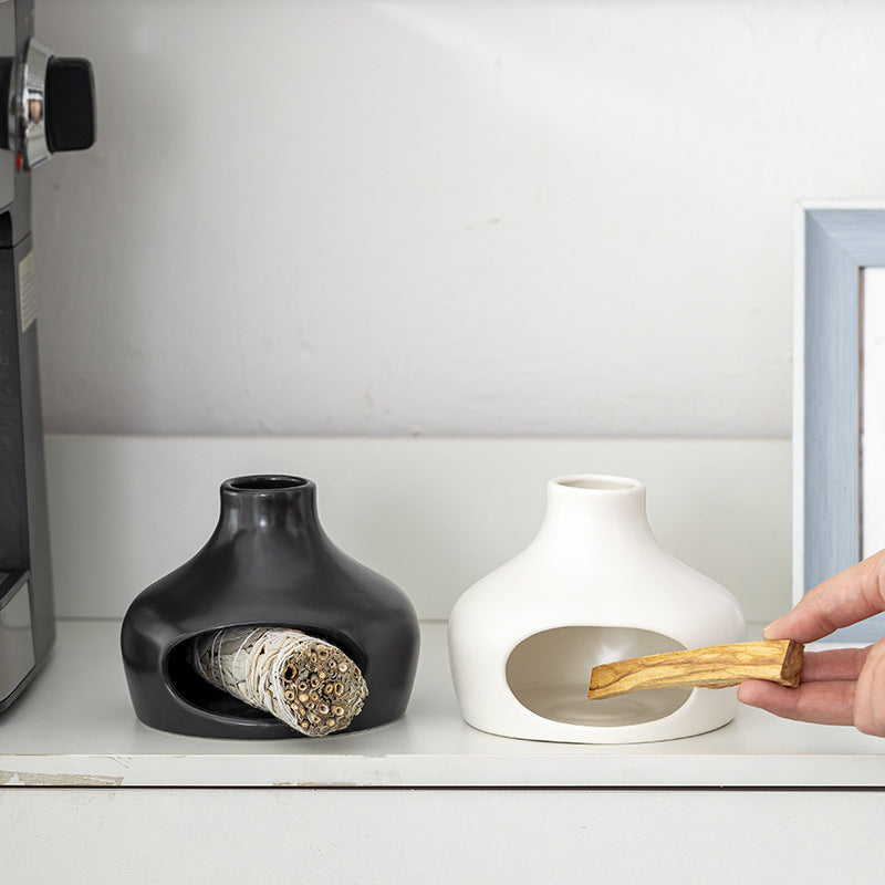 Black and white ceramic smudge burners displayed together on a shelf