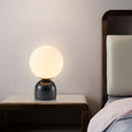 Black marble globe table lamp with frosted glass shade on bedside table