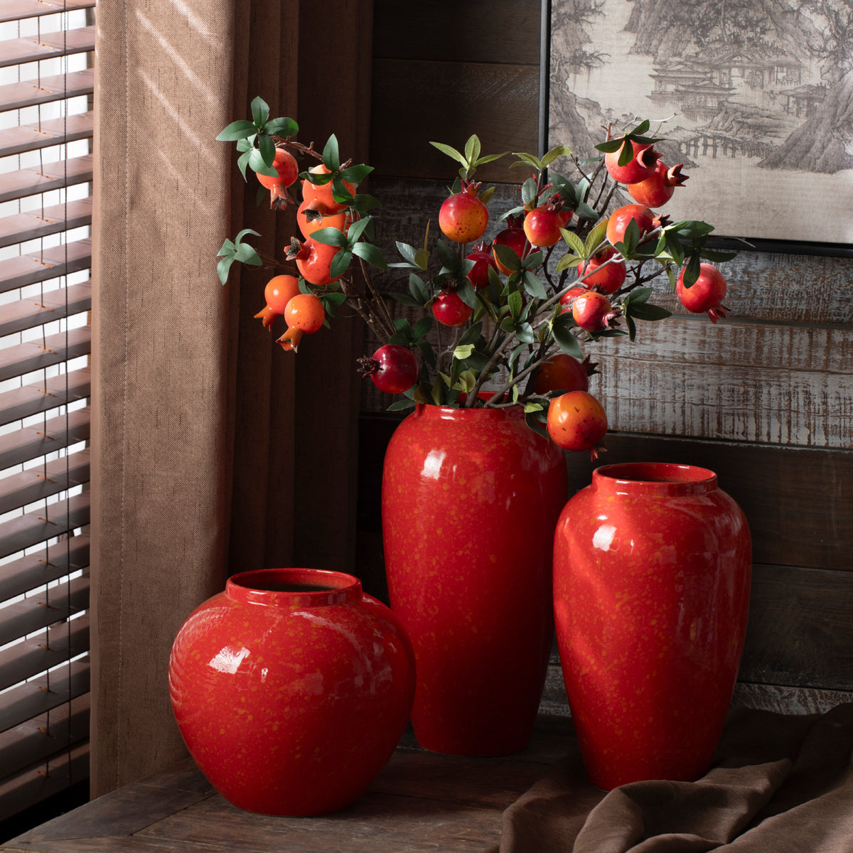 Red ceramic vase trio styled with pomegranate branches