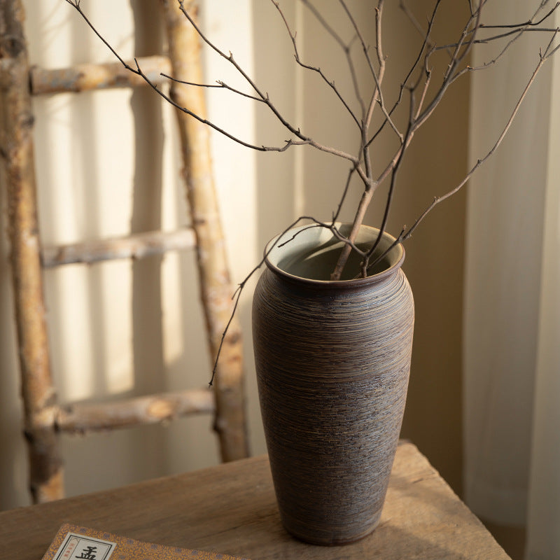Brown horizontal-ribbed ceramic vase with sculptural branch arrangement