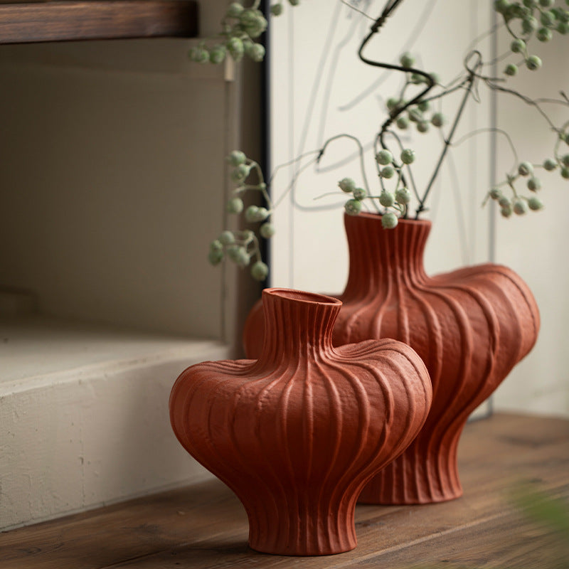 Small and large terracotta red ribbed ceramic vases styled with branches