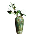 Tall green patina ceramic vase with leafy branch arrangement