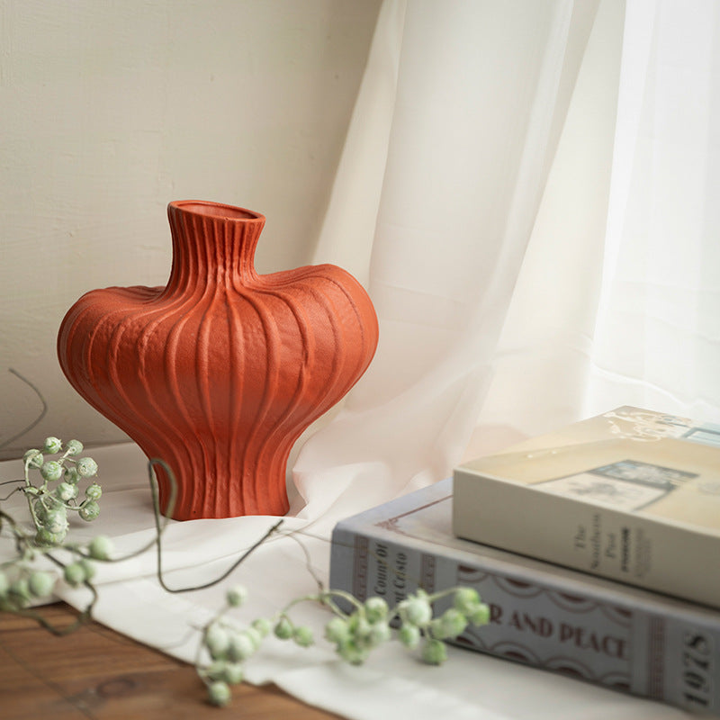 Terracotta red sculptural ceramic vase styled beside books