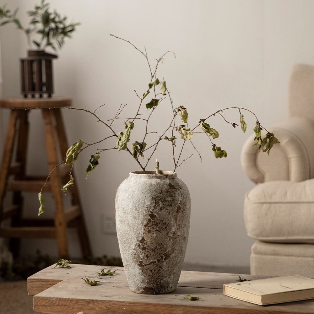 Weathered stone-effect ceramic vase styled beside neutral armchair