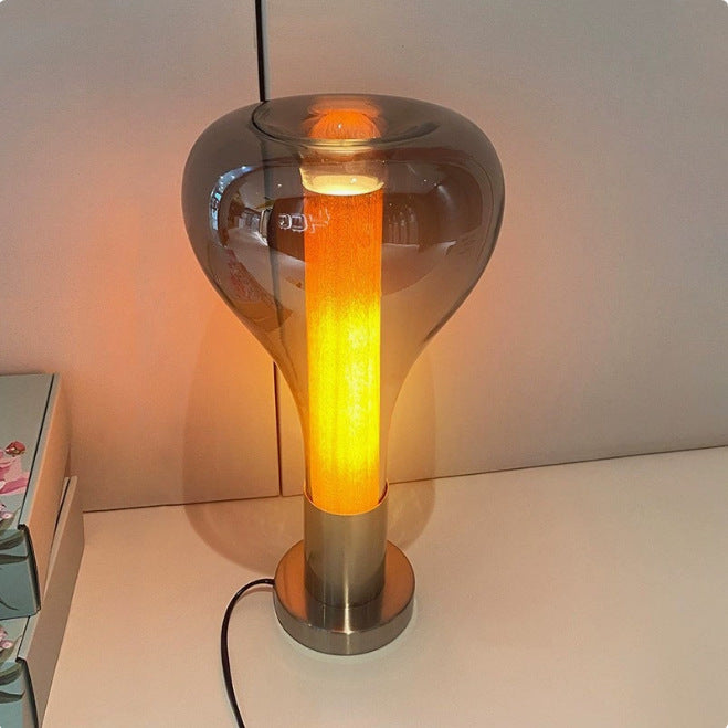 Sculptural glass capsule bedside lamp glowing warm amber