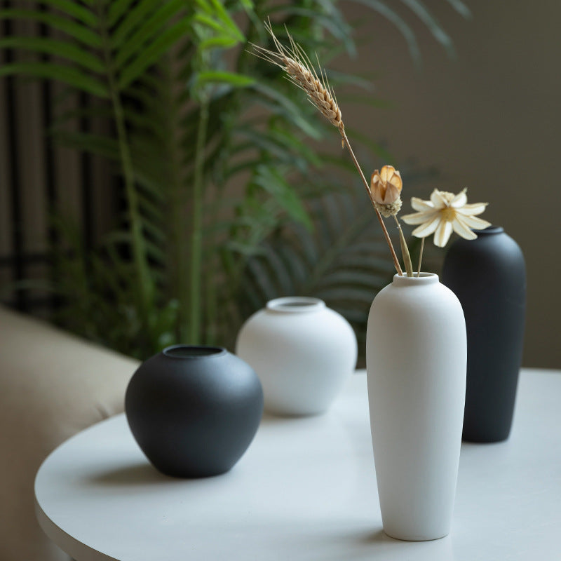 Matte black and white sand-texture ceramic vase set on round table