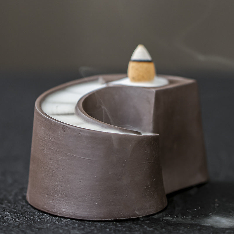 Backflow incense smoke flowing through ceramic spiral burner