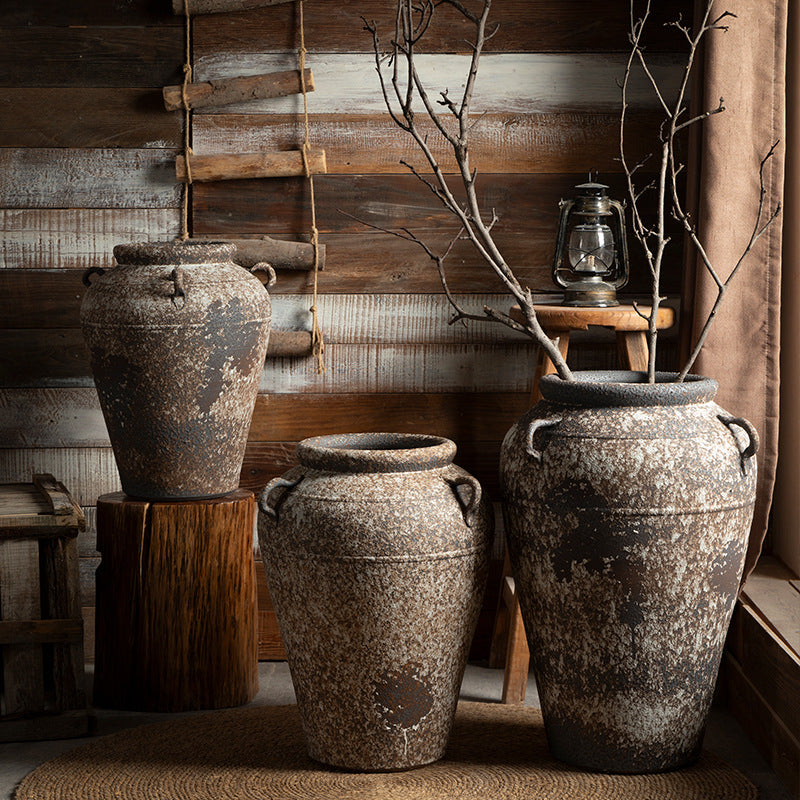 Three rustic weathered double-handle ceramic urn sizes in a cabin interior