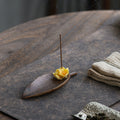 Fallen leaf osmanthus ceramic incense holder styled on a dark wood tea table