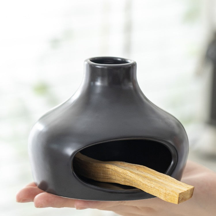 Matte black ceramic Palo Santo burner holding sacred wood in open front chamber