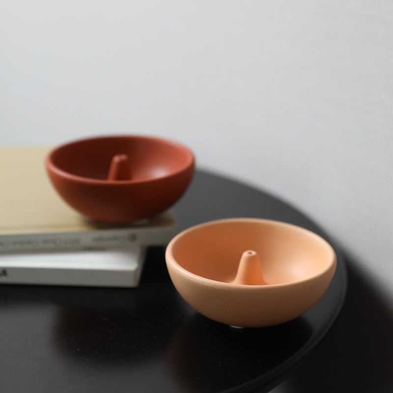 Terracotta red and light coffee round ceramic incense bowls styled on a black table