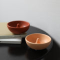 Terracotta red and light coffee round ceramic incense bowls styled on a black table