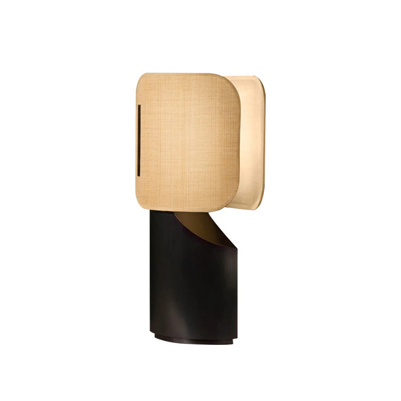 Sculptural black metal table lamp with softly glowing layered fabric shade