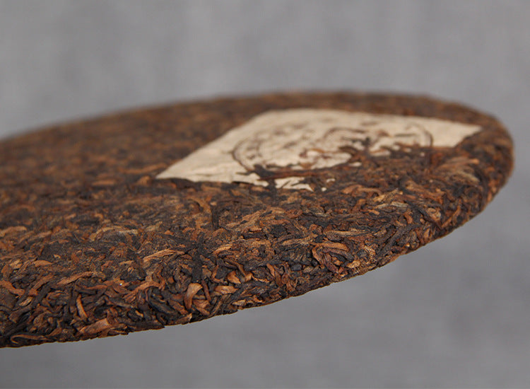 Stacked aged ripe Pu-erh tea cakes with visible golden bud leaf material