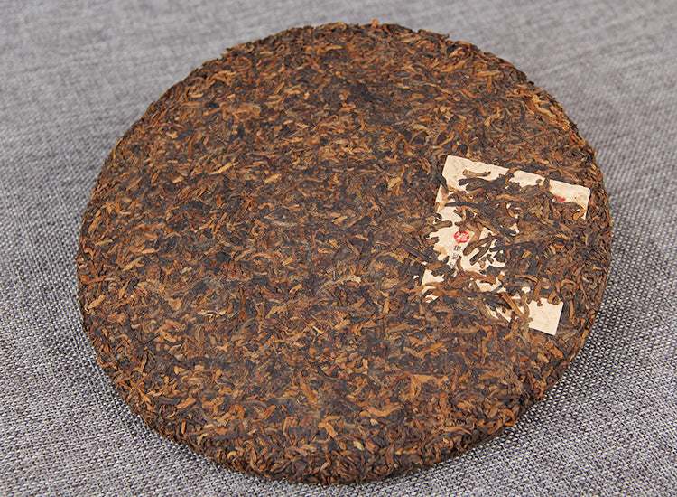 Unwrapped 357g aged ripe Pu-erh tea cake with dark compressed leaves