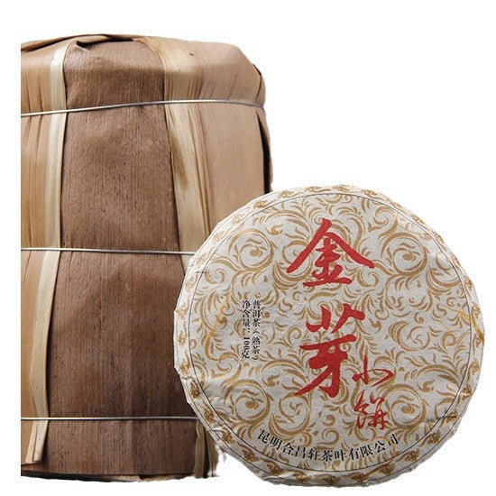 2009 Golden Bud ripe Pu-erh 100g tea cake beside traditional stacked packaging