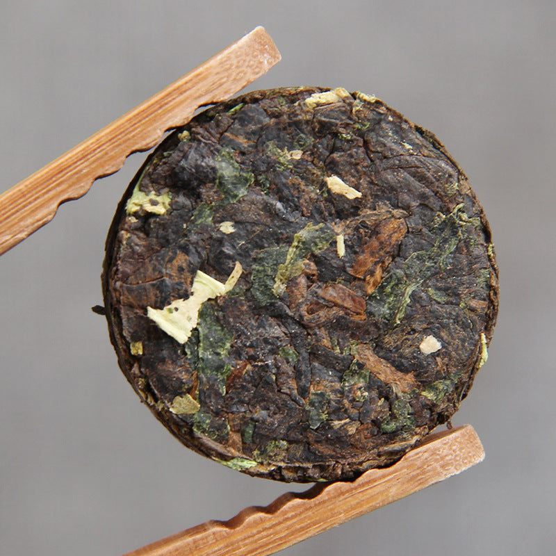 Unwrapped sticky rice aroma ripe Pu-erh mini cake showing compressed tea and Nuo Mi Xiang leaves