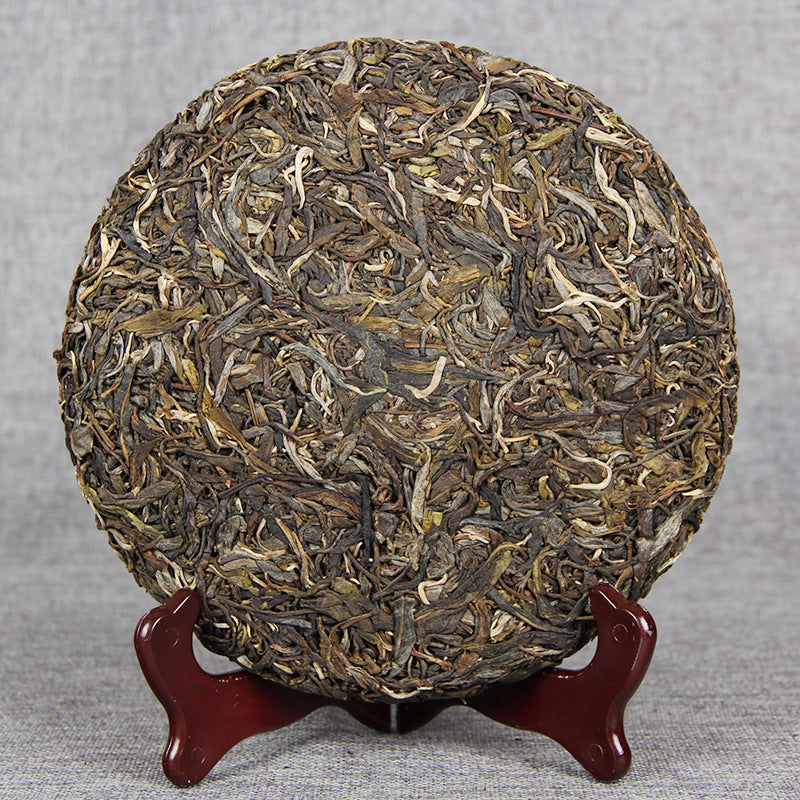 Unwrapped 2017 Xigui-style raw Pu-erh tea cake showing compressed spring tea leaves