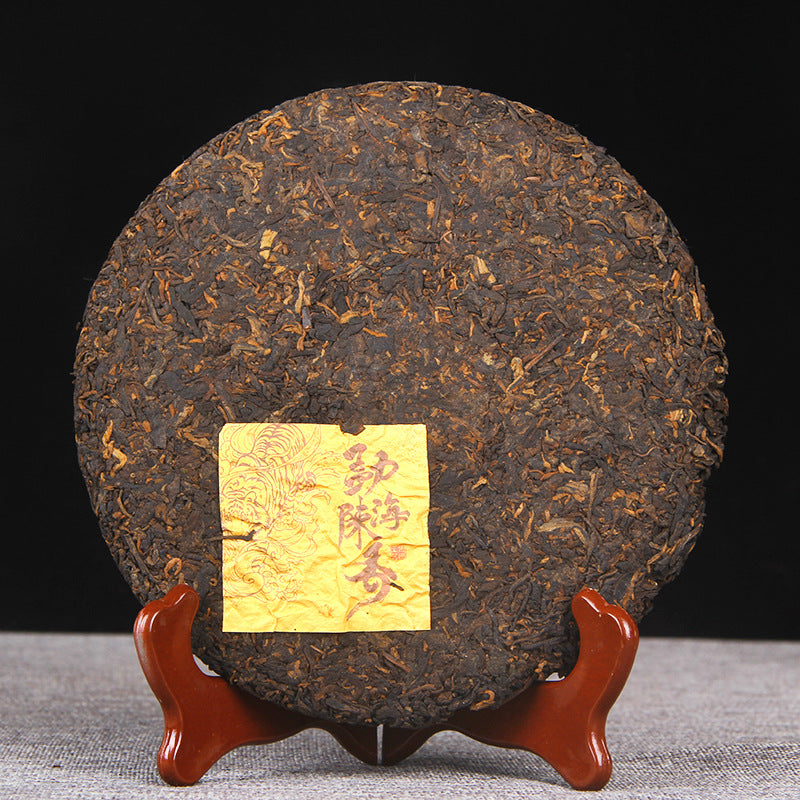 Unwrapped 357g Menghai ripe Pu-erh tea cake showing compressed fermented leaf surface