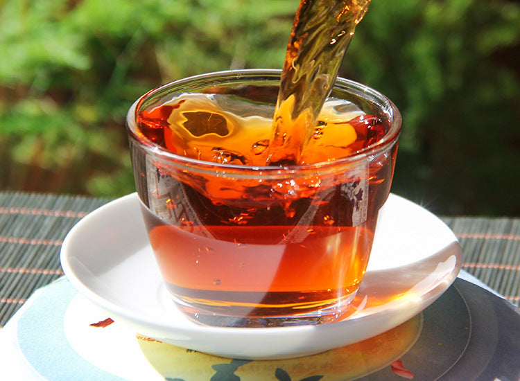 Deep red Banzhang ripe Pu-erh liquor poured into a glass cup
