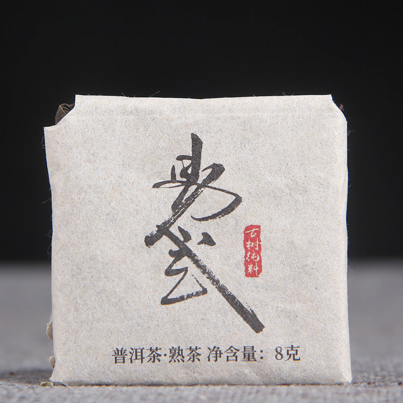 Unwrapped 2022 Yiwu ripe Pu-erh mini square showing compressed leaf