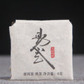 Unwrapped 2022 Yiwu ripe Pu-erh mini square showing compressed leaf