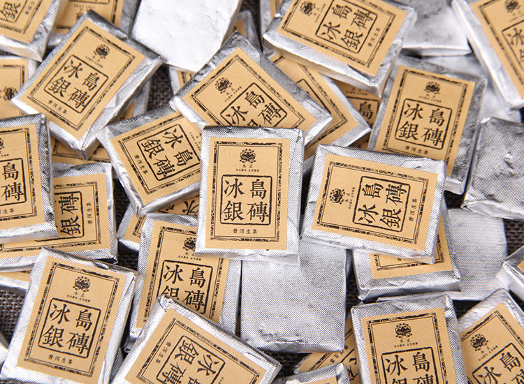 Pile of individually wrapped 2023 Bingdao Silver Brick raw Pu-erh mini squares