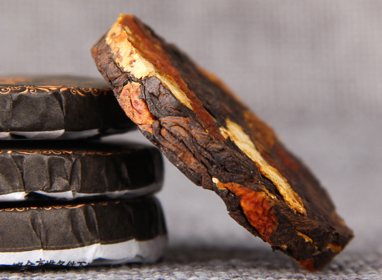 Aged tangerine peel Chenpi pieces visible in ripe Pu-erh mini tea cake