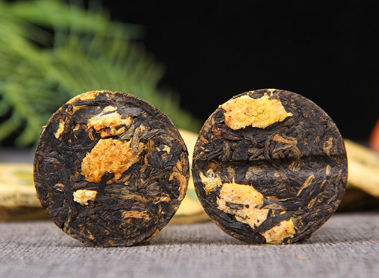 Two unwrapped Cili chestnut rose Dianhong black tea mini cakes with visible fruit pieces