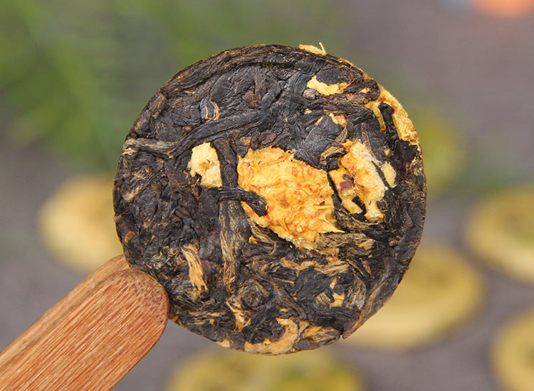 Single unwrapped Cili chestnut rose Dianhong black tea mini cake on a wooden tea scoop