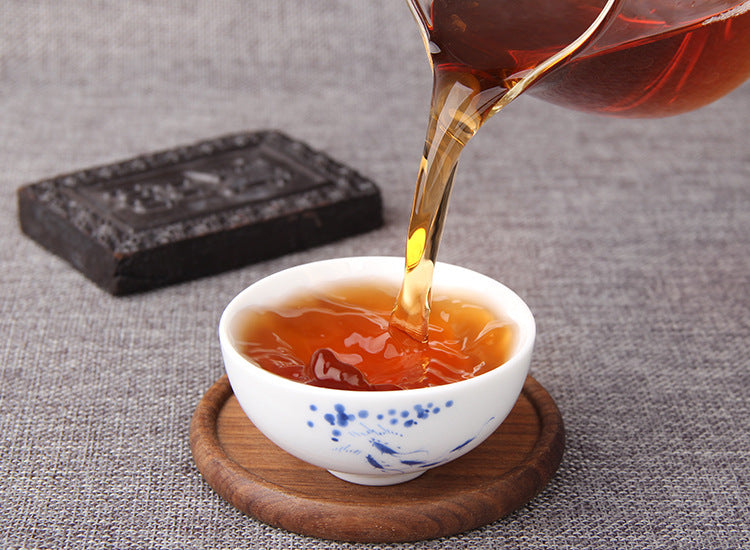 Instant Pu-erh tea paste brick beside a cup of deep amber tea liquor