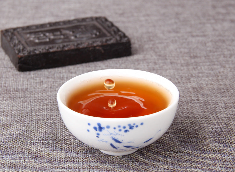 Cup of clear red-brown ripe Pu-erh tea prepared from soluble tea paste