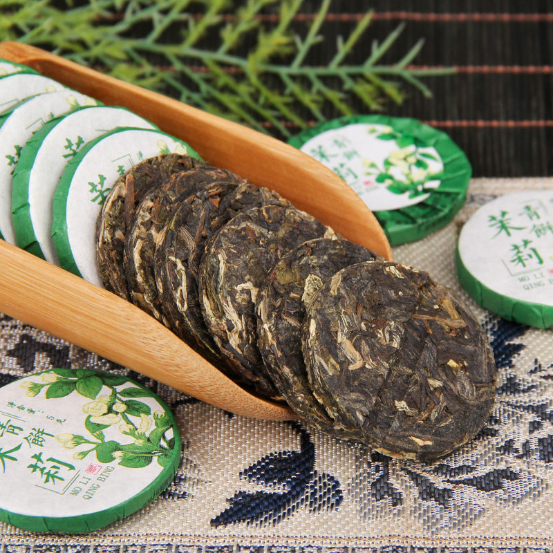 Unwrapped 2025 jasmine aroma raw Pu-erh mini tea cakes showing compressed tea