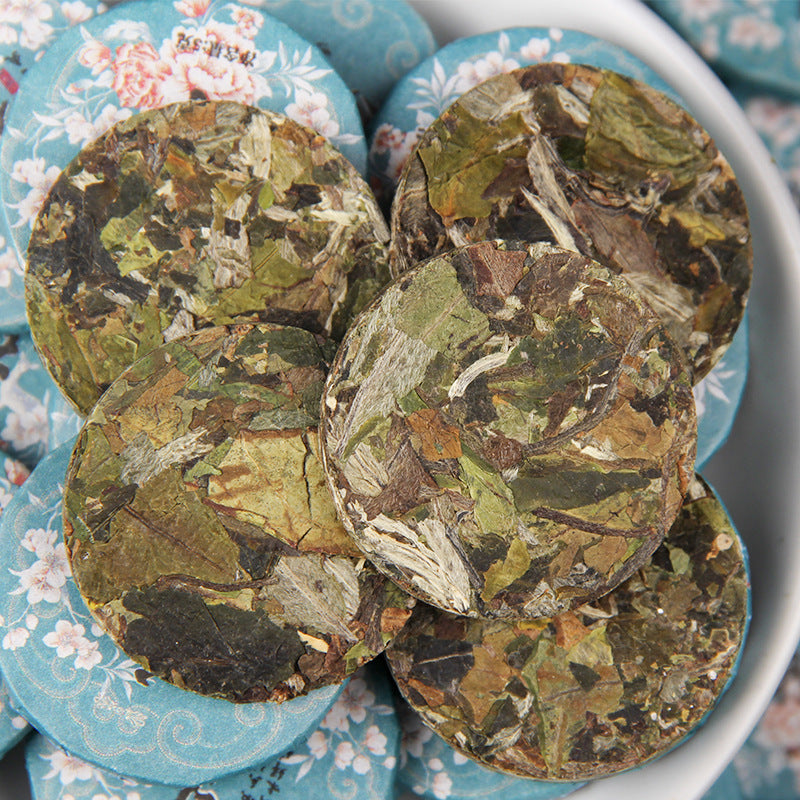Unwrapped 2025 Yunnan Bai Mudan white tea mini cakes showing compressed leaves