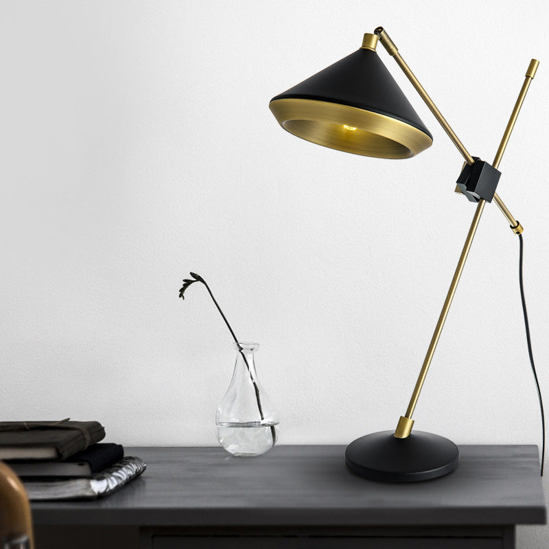 Adjustable black cone-shade table lamp with antique-brass frame on a modern desk