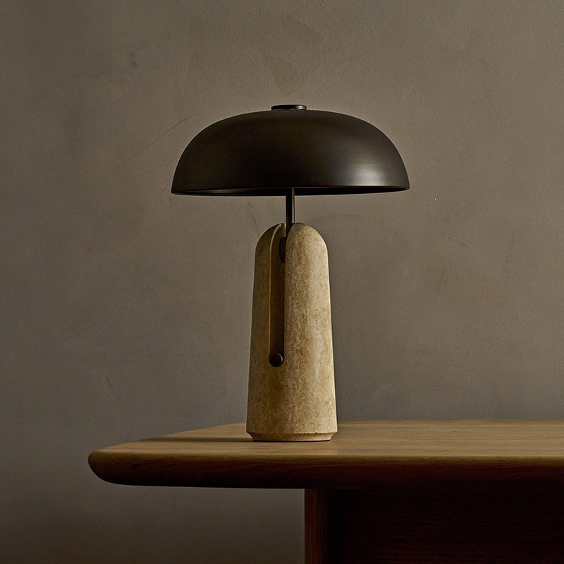 Warm ambient black dome travertine table lamp on a wooden table